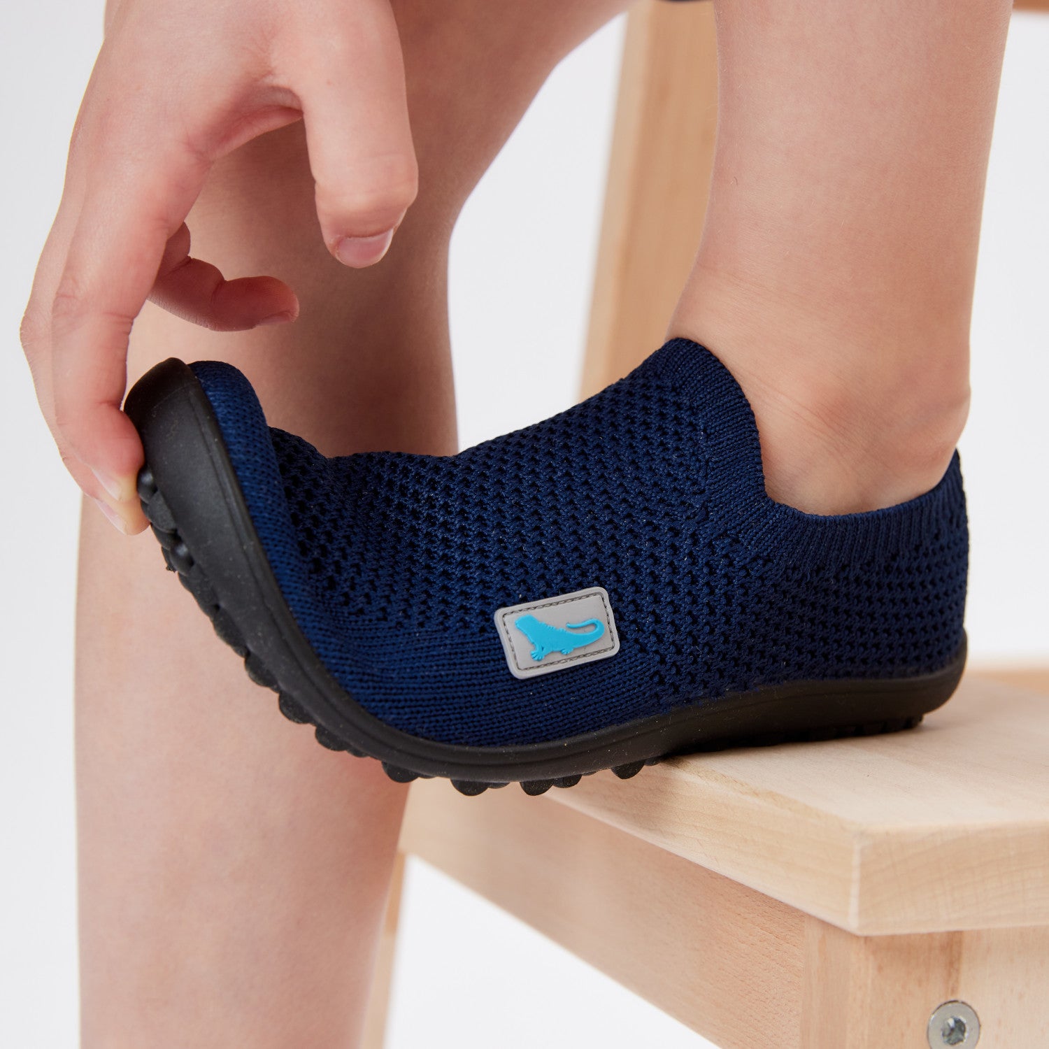 Leguanito Scio Leguano Kinder Barfußschuhe Slipper in Blau (Größen 29 bis 34) – im Alltag getragen von einem Kind, das spielerisch in einer Wiese unterwegs ist. Erhältlich im Barfußschuhe Onlineshop barfussweltan.shop.